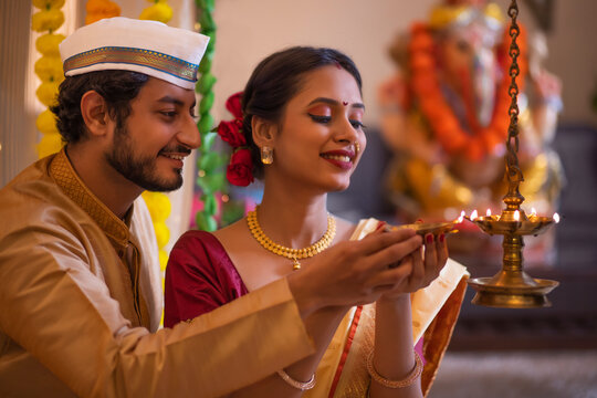 Maharashtrian couple lighting oil lamp on the occasion of Ganesh Chaturthi