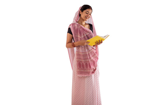Portrait of a woman reading book while standing against white background