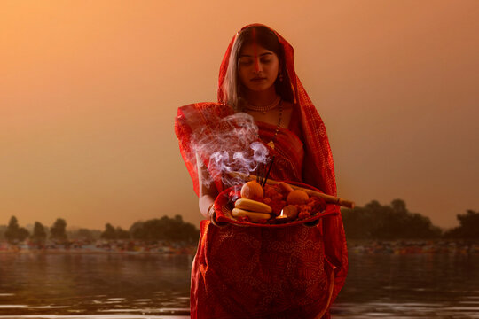 woman from Bihar offers prayers to the  sun  in the  early morning hours   during  Chhath Puja festival