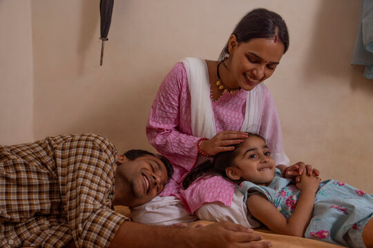Mother stroking her daughter's head while her husband lying with head on her lap