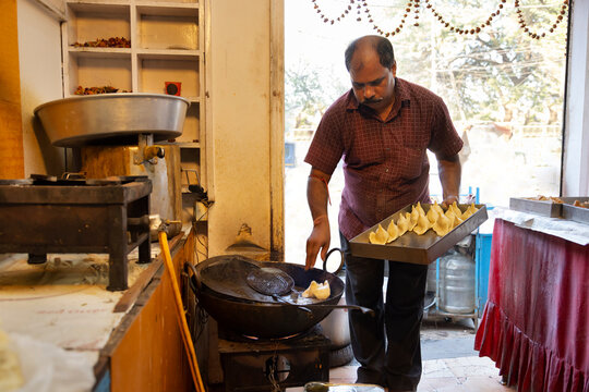 Owner of a sweet shop known as a Halwai  making Samosas, a popular Indian snack in the  kitchen of his sweet   shop