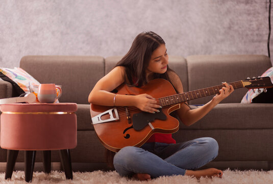 Teenage girl playing guitar at home