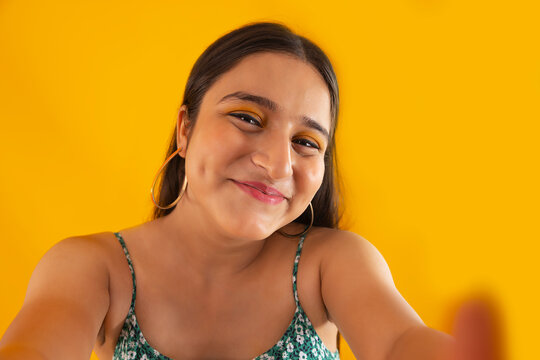 Closeup portrait of a teenage girl with arms outstretched towards camera against yellow background
