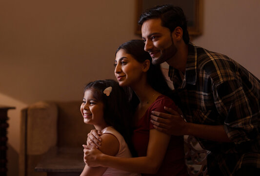 Happy young couple spending good time together with their daughter at home