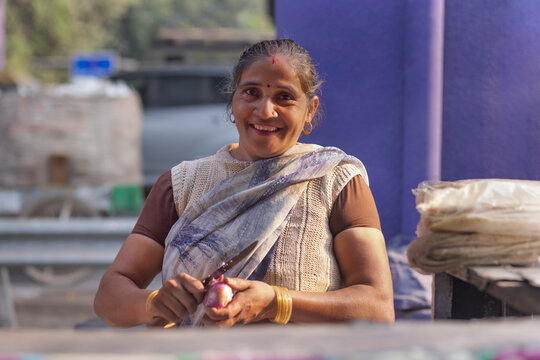 Female vendor peeling an onion with knife at her roadside food stall