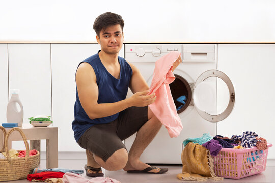 Portrait of a tired young man doing laundry