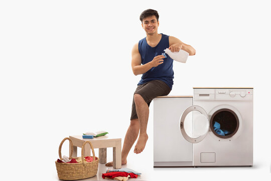 Portrait of young man pouring detergent 
