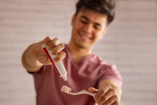 Young Man squeezing out toothpaste on a toothbrush