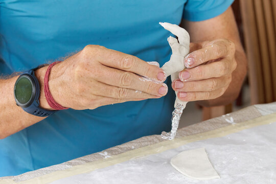 Close up of male hands sculpting clay figure at table. Handmade pottery, creative workshop and ceramics hobby concept.