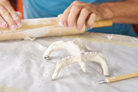 Close up of male hands sculpting clay figure at table. Handmade pottery, creative workshop and ceramics hobby concept.