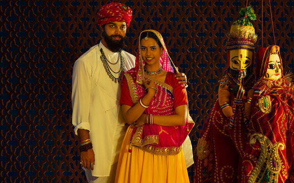 Portrait of a Rajasthani couple with puppets in the foreground. 