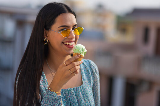 Portrait of young woman eating ice cream in cone