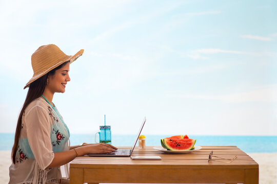 Woman using laptop while sitting at beach