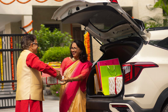 Senior couple unloading Diwali gifts from car trunk after shopping