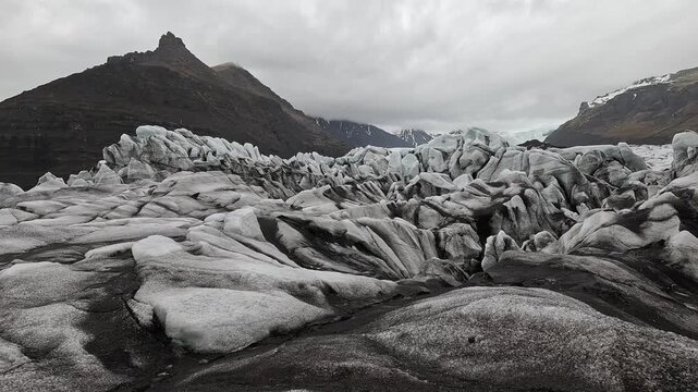 Svinafellsjokull on-glacier ash-covered ice surface with jagged seracs and blue ice peaks, Iceland