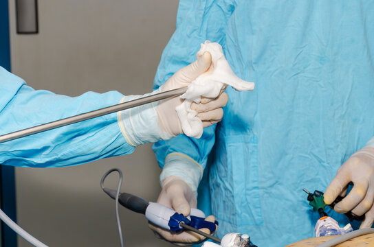 Surgeon wiping laparoscopic camera lens during minimally invasive surgery in operating room