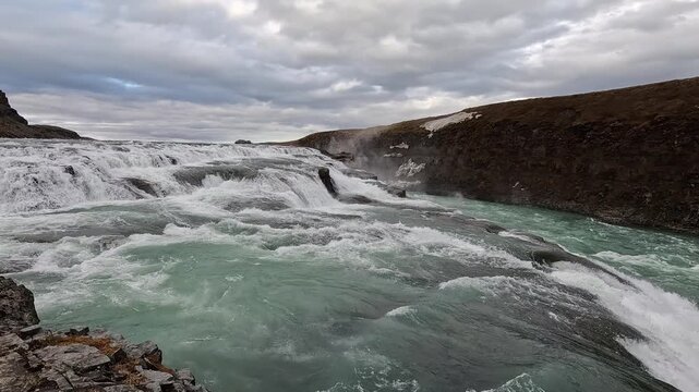 Gullfoss upper tier close-up, glacial green Hvita river cascading over broad basalt steps, Iceland