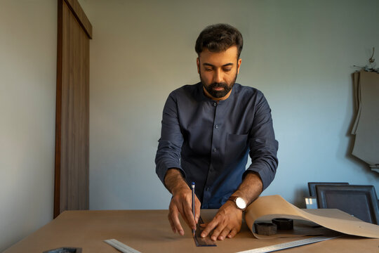 A male designer making patterns for a menswear collection in his studio 