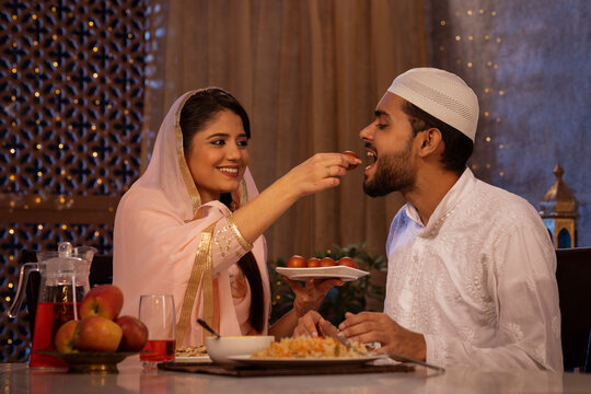 Muslim woman feeding a gulab jamun to her husband 