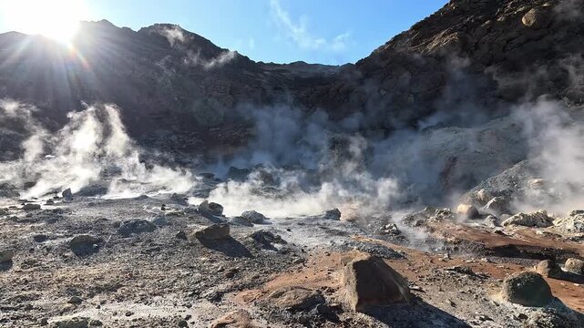 Low angle wide shot of steaming fumarole field across rocky volcanic floor at Seltun, Reykjanes Peninsula, Iceland