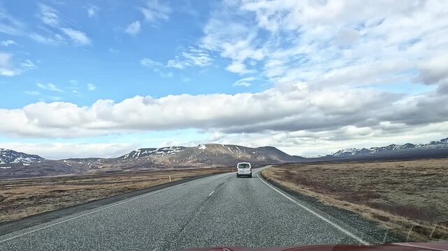 Dashcam POV following white van on Route 36 through open moorland with snow-streaked volcanic hills both sides, Iceland