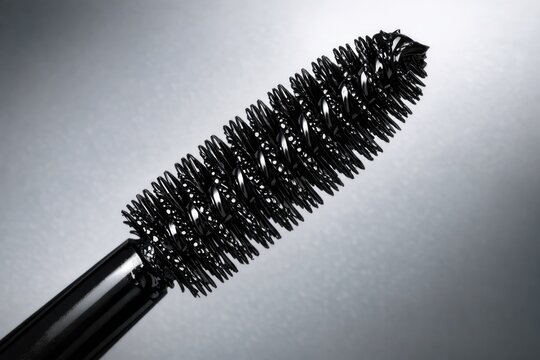 Close-up shot of a mascara brush on a gray background