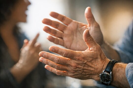 A couple sits at a table with their hands up, suggesting surrender or acquiescence