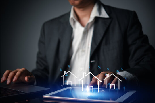 businessman using tablet laptop analyzing real estate market growth hologram house icon upward arrow percentage sign property investment mortgage interest rate rising financial finance business wealth