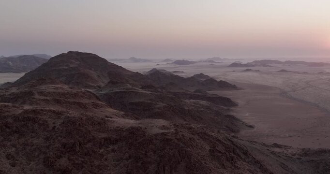 Aerial view flying over rugged red granite mountains at dusk in the Namib-Naukluft National Park, western Namibia.