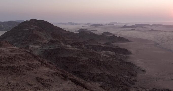 Aerial view flying over rugged red granite mountains at dusk in the Namib-Naukluft National Park, western Namibia.