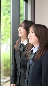[スローモーション]窓の外を見つめる日本人女子高校生複数 将来・進路・希望などの青春や学校イメージのクローズアップの縦動画
