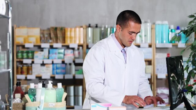  Young man pharmacist working with computer in pharmacy