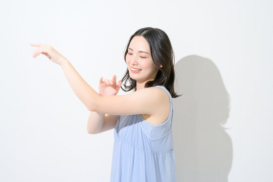白背景で腕に日焼け止めを塗る日本人女性のビューティイメージ
