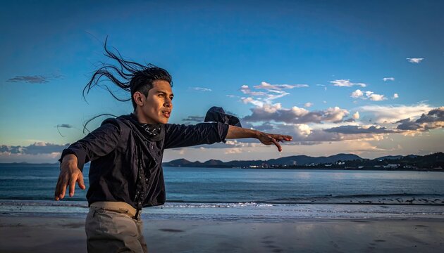 Man with windblown hair on beach at sunset.