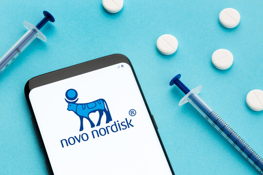 Galicia, Spain; June 8, 2020 : phone showing Novo Nordisk logo on screen with pills and syringes on blue background