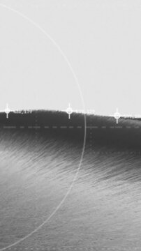 Vertical monochrome topography matrix grid moves with fine radar scanning circles and telemetry coordinate data parameters over a gray hillside
