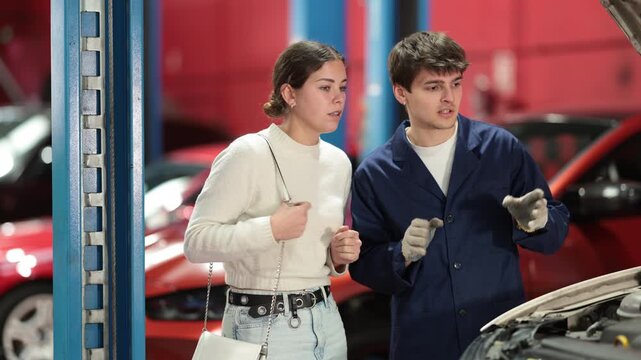 Female mechanic makes a plan together with a male mechanic about the repair and maintenance of the car. Mechanics plan to inspect the engine, change the oil and check the mechanics. High quality 4k
