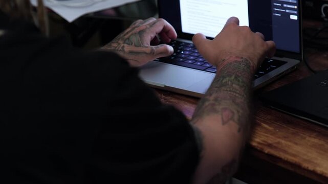 Person types on laptop while sitting at wooden desk in a cozy room during day