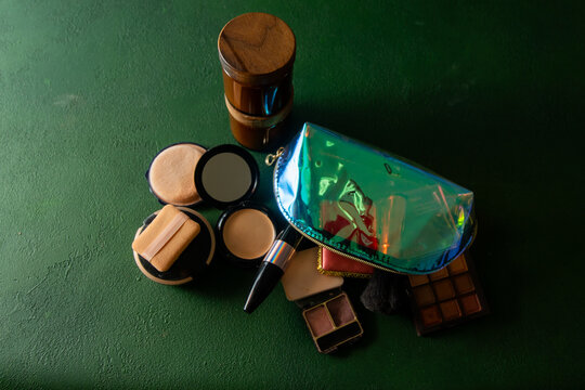 Makeup Collection with Iridescent Bag, Eyeshadow Palette, and Beauty Products Cosmetic on Green background.