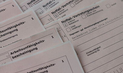 A close-up view of German medical forms with text such as 'Arbeitsunfähigkeitsbescheinigung' (Work...