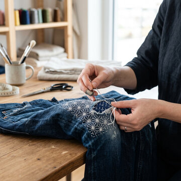 Artisan repairing denim jeans with traditional sashiko stitching technique