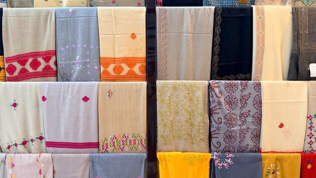 Colorful Pakistani fabric store shelves with patterned and embroidered unstitched dress materials.