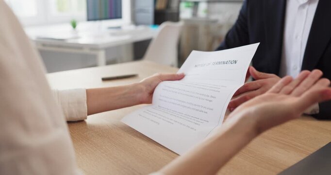Employee reads termination notice in office. Manager reviews contract termination in HR meeting, covering separation paperwork and layoffs for workplace communications. Strong concept of job loss.