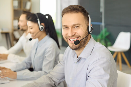 Agent with headset provides customer service support. Smiling operator in a professional office works in a focused team, managing hotline communication. Clear concept of customer support.