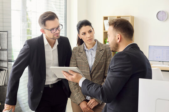 Business executives meeting, tablet strategy discussion. Three colleagues review data on a tablet presentation and align goals in a modern office. Clear teamwork and collaboration concept.