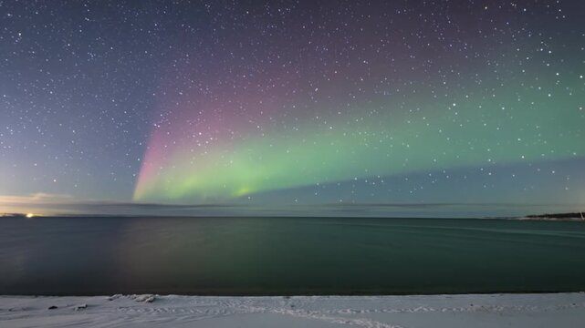 Vivid green and violet aurora ripples across a starry sky, mirrored on a calm frozen lake at night. Perfect for travel marketing, nature documentaries and meditation content.