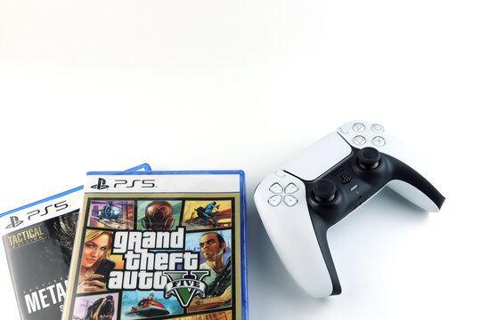 PS5 DualSense controller on white table with Grand Theft Auto V (GTA 5) PlayStation 5 game case background of Modern gaming popular console title, entertainment, technology, and video game collection.