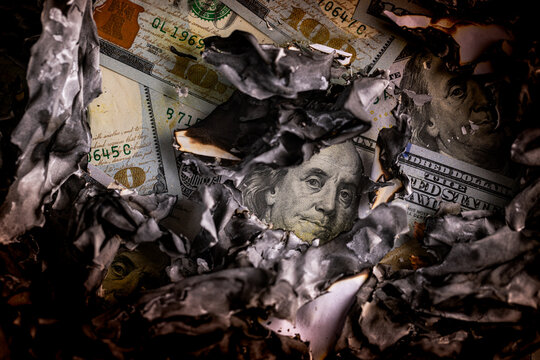 Close-up of US one hundred dollar bills covered with burnt ash and charred paper remnants