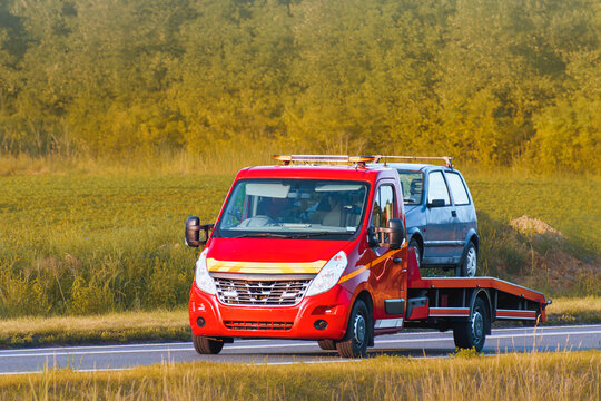 Yellow truck towing damaged car from roadside