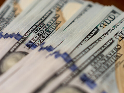 Stack of Hundred Dollar Bills on Wooden Surface